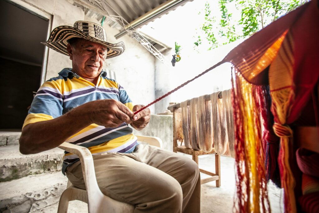 Man sitting down and weaving bright fabric