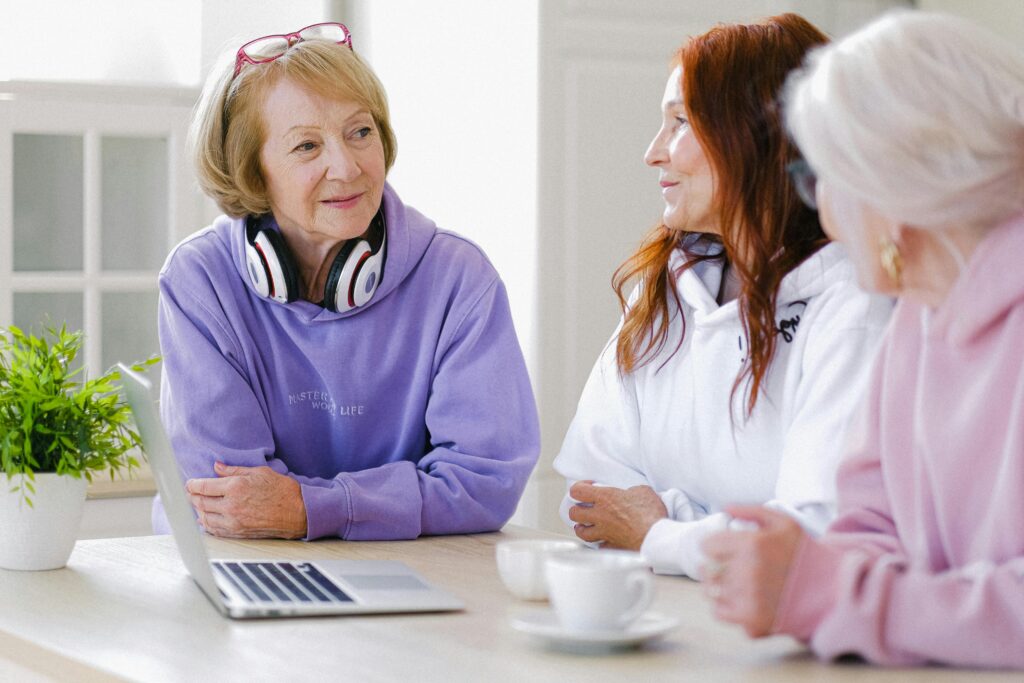 3 women discussing something at the kitchen table over coffee while looking at a computer