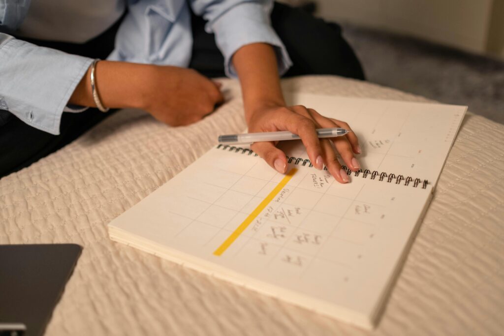 Person holding a pen and writing in a calendar organizer.