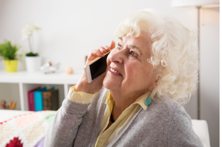 Woman with light hair and a smile calling on a cell phone with a happy expression